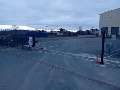 Entrée du parking du Humeau, avec clôture et portail ouvert