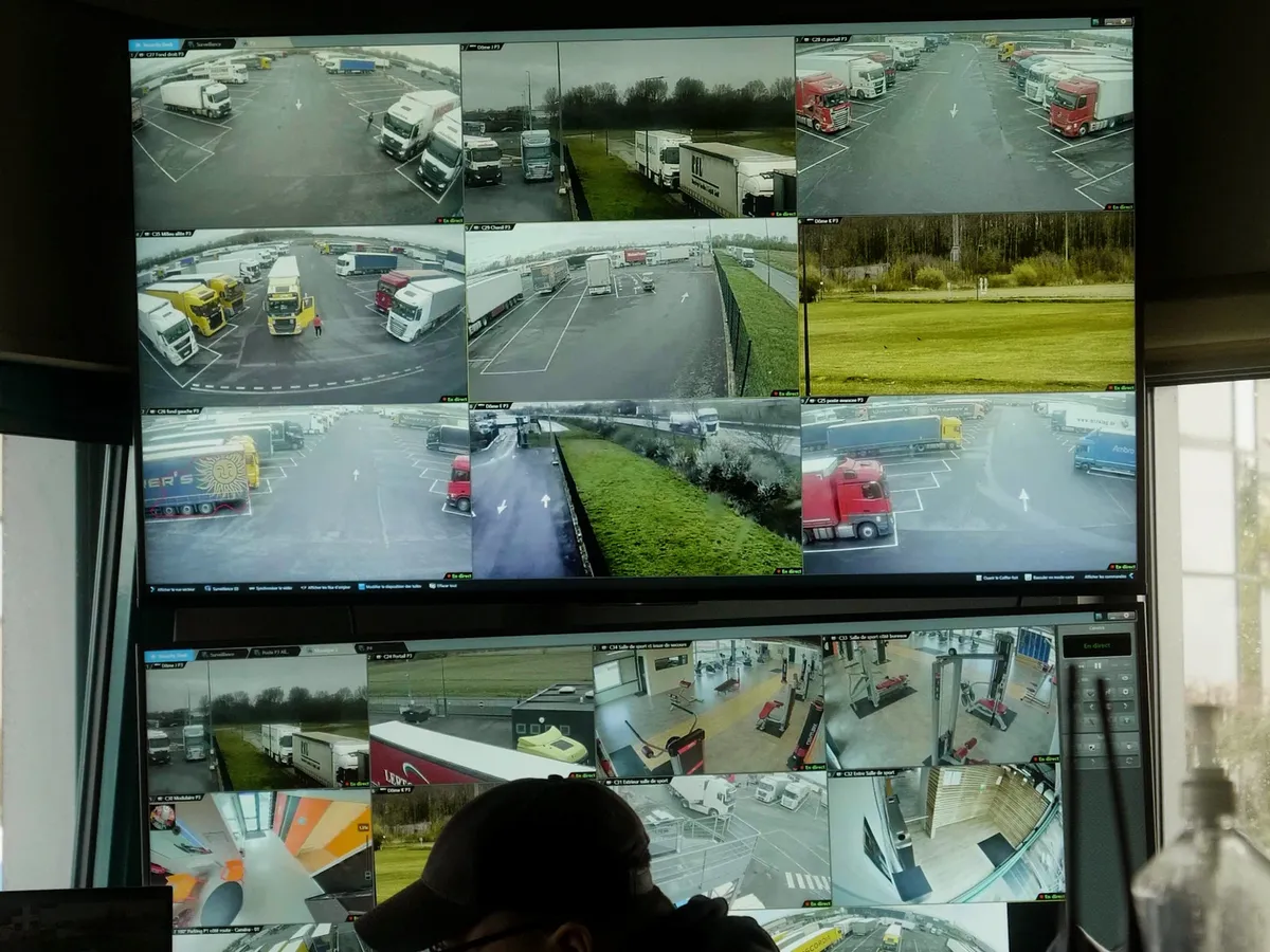 Video surveillance monitors showing parked trucks and access lanes in a truck parking area