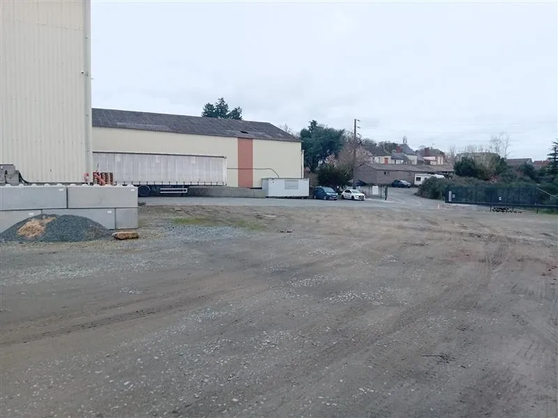 Aire de stationnement à Humeau, avec des bâtiments industriels et une remorque à côté de l'espace dégagé.